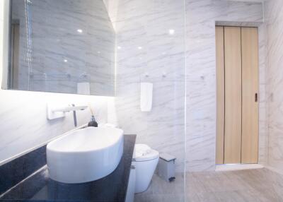 Modern bathroom with marble walls, vessel sink, and wall-mounted mirror