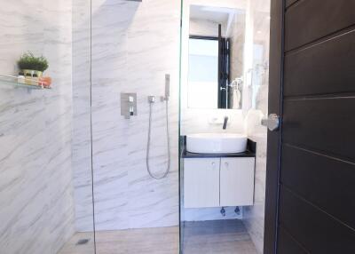 Modern bathroom with marble walls, glass shower, and vanity