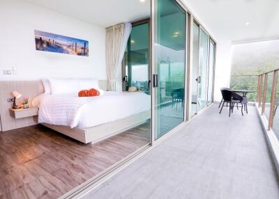 Well-lit modern bedroom with sliding glass doors opening to a balcony