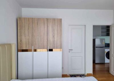 Modern bedroom with wardrobe and view into adjacent kitchen