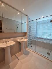 Modern bathroom with two sinks, a glass shower enclosure, and a bathtub