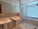 Modern bathroom with two sinks, a glass shower enclosure, and a bathtub