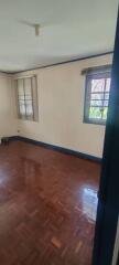 Empty bedroom with polished wood floors and windows with blinds