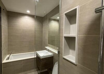 Modern bathroom with glass shower, bathtub, and toilet