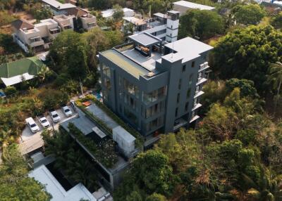 Aerial view of a modern apartment building surrounded by greenery