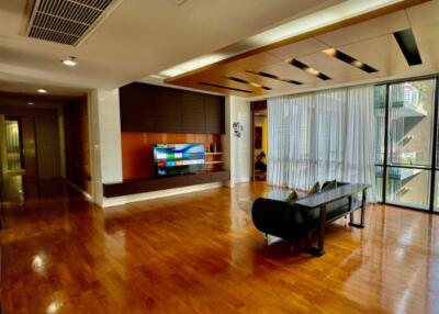 Modern living room with wooden floor, large TV, and floor-to-ceiling windows