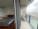 Modern bedroom with glass door leading to a balcony overlooking the city