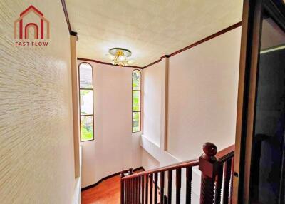 Staircase with wooden railings and large windows