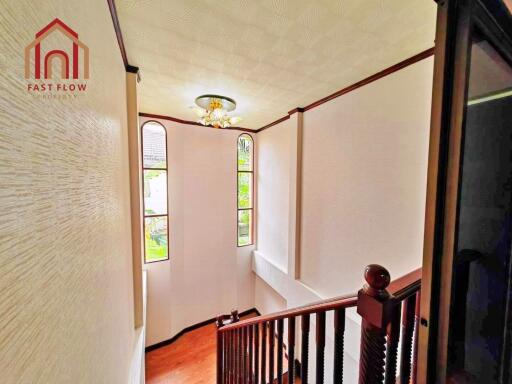 Staircase with wooden railings and large windows