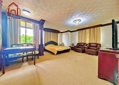 Spacious master bedroom with large windows, bed, seating area, and television