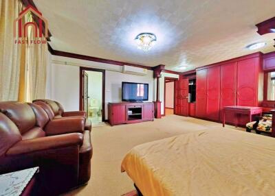 spacious bedroom with brown furniture, wardrobe, and TV