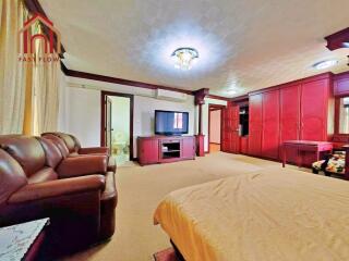 spacious bedroom with brown furniture, wardrobe, and TV