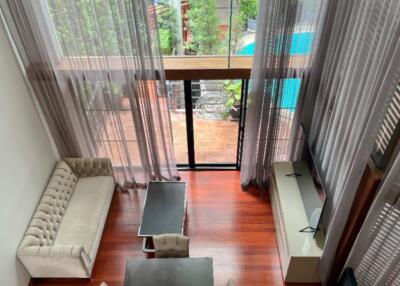 High-ceiling living room with large windows and modern furnishings