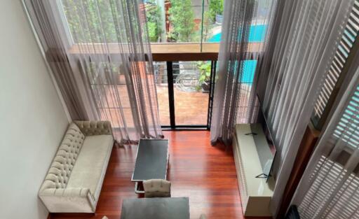 High-ceiling living room with large windows and modern furnishings