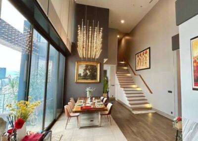 Modern dining area with high ceiling and staircase