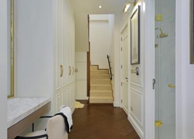 Elegant hallway with white walls, dark wooden flooring, and a staircase leading to the upper floor.