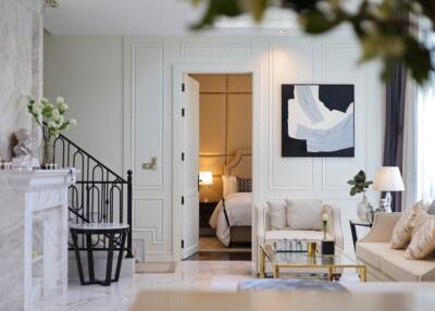 Elegant living room with marble fireplace, staircase, and view into a bedroom