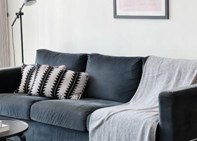 Living room with a black couch, decorative pillows, and a standing lamp