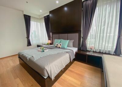 Well-lit bedroom with wooden floors, large windows, and tasteful decor