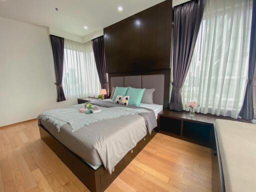 Well-lit bedroom with wooden floors, large windows, and tasteful decor