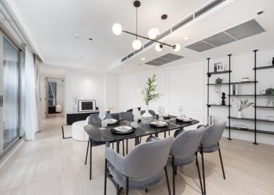 Modern dining area with elegant black table and chairs, open to a living room and sliding glass doors