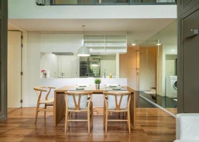 Modern dining area adjacent to kitchen with wooden furniture and contemporary lighting