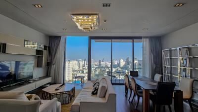 Modern living room with city view, chandelier, and dining area