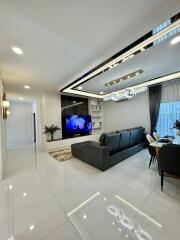 Modern living area with sectional sofa, TV, and dining space