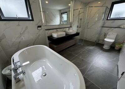 Modern bathroom with a large bathtub, double sink, and glass shower