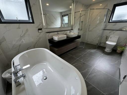 Modern bathroom with a large bathtub, double sink, and glass shower