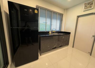 Modern kitchen with black refrigerator and tiled countertops