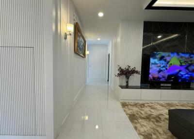 Modern living room with a wall-mounted TV and a hallway