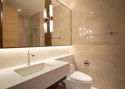 Modern bathroom with marble walls, large mirror, and sleek fixtures