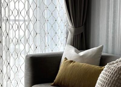 Cozy living room corner with modern grey couch, decorative pillows, and elegant curtains