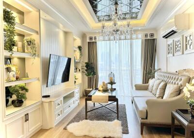 Elegant living room with decorative ceiling, chandelier, and wall-mounted TV