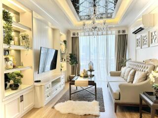 Elegant living room with decorative ceiling, chandelier, and wall-mounted TV