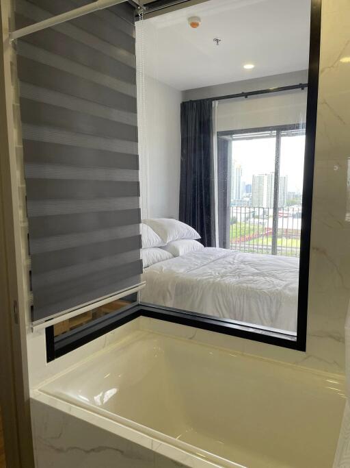 Bedroom with adjacent bathroom view and cityscape backdrop