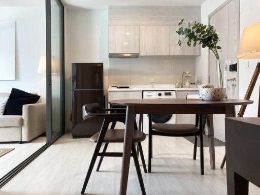 Modern kitchen and dining area with wooden dining table and chairs, integrated fridge, washer, sink, and cabinetry