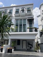 Front view of a multi-storey white building with balconies and potted plants