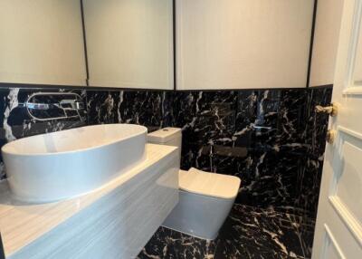 Modern bathroom with black marble tiles and white fixtures