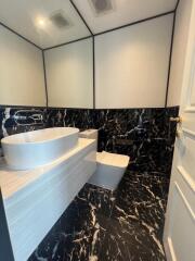 Modern bathroom with black marble tiles and white fixtures