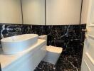 Modern bathroom with black marble tiles and white fixtures