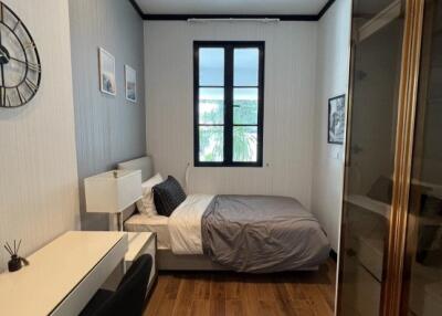 A well-lit bedroom with a desk, chair, bed, and wall decorations