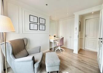 Bright bedroom with armchair, ottoman, and work desk