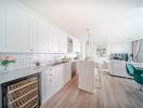 Modern open-plan kitchen and living area with white cabinets and wooden flooring