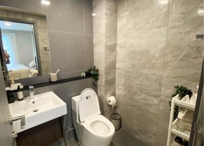 Modern bathroom with a toilet, sink, and wall-mounted mirror