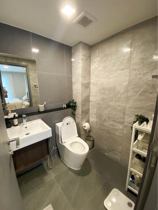 Modern bathroom with a toilet, sink, and wall-mounted mirror