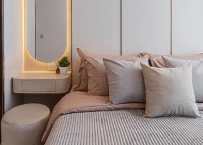 Modern bedroom with grey and beige tones, accented with a vanity area and natural light.