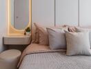 Modern bedroom with grey and beige tones, accented with a vanity area and natural light.