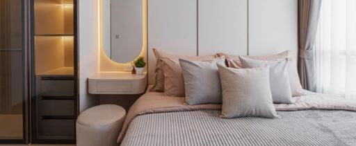 Modern bedroom with grey and beige tones, accented with a vanity area and natural light.